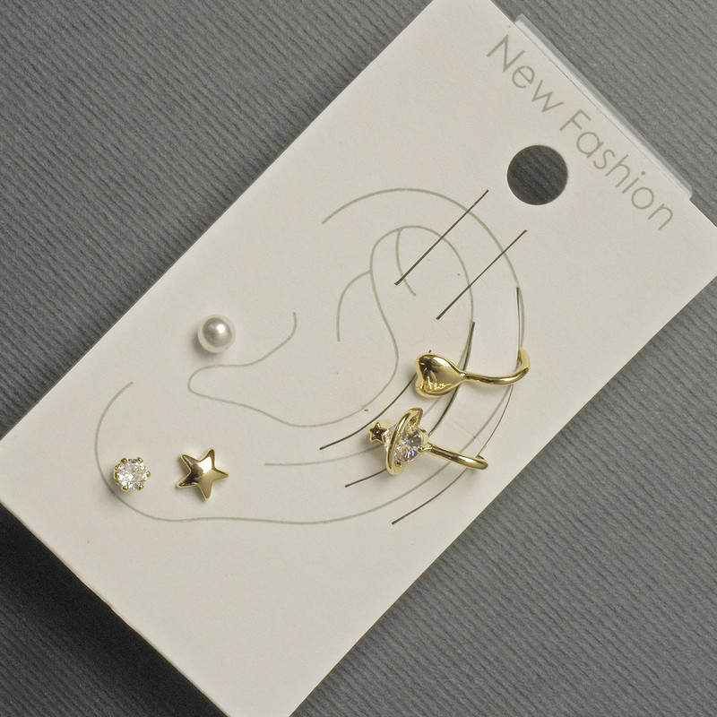 Earrings 'Studs and Connets' on earlobe with golden metal, white rhinestones and pearl